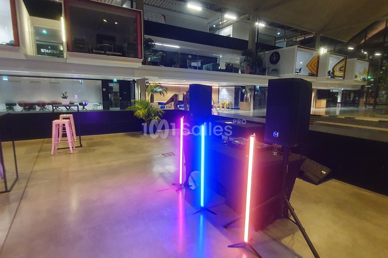 Poste de DJ avec éclairage LED coloré dans un espace moderne et ouvert, entouré de mobilier et de baies vitrées.