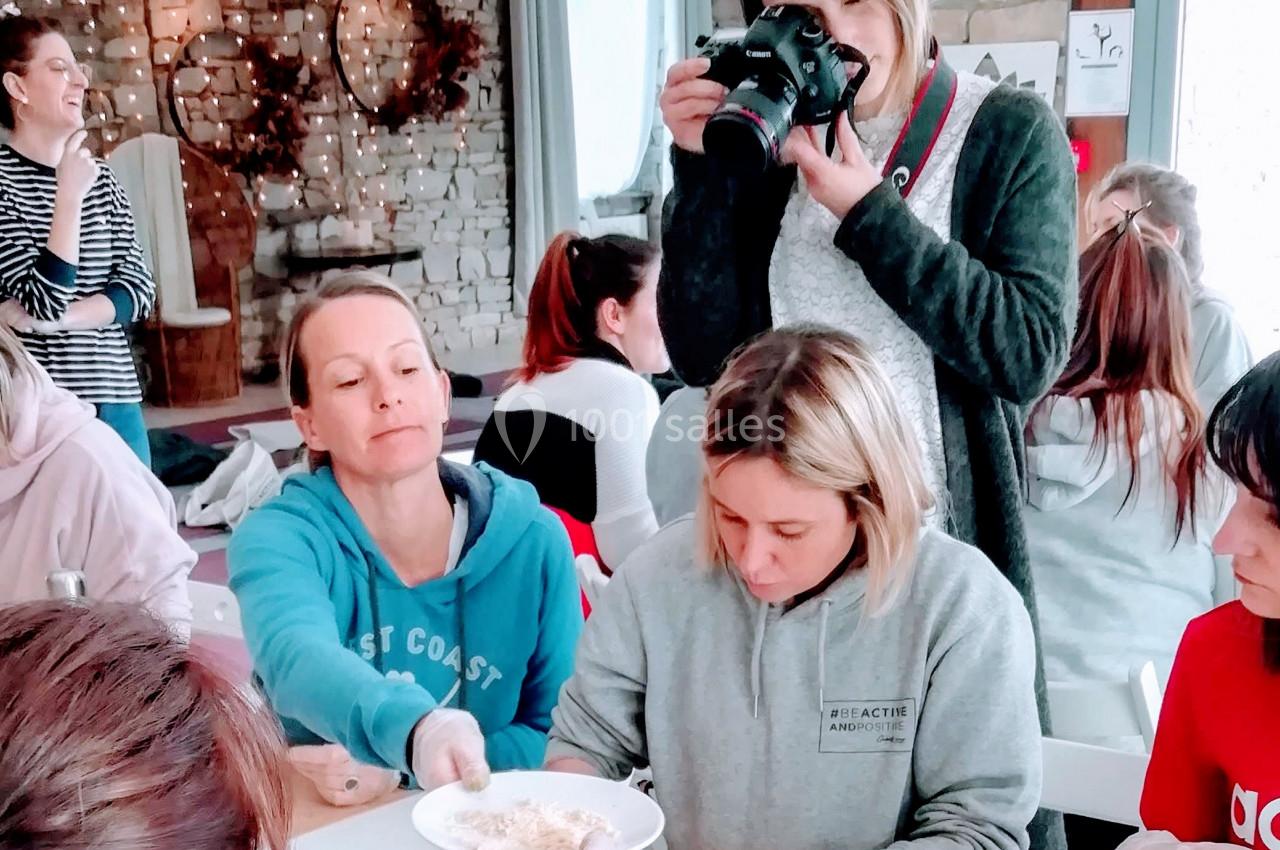 Un groupe de personnes participe à un atelier créatif autour d'une table, une femme prend des photos.