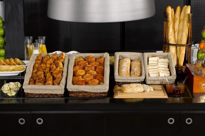 Buffet de viennoiseries et pains variés disposés sur un comptoir noir avec jus de fruits en arrière-plan.