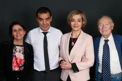 Un groupe de personnes pose devant une bannière, une femme au centre tient un diplôme.