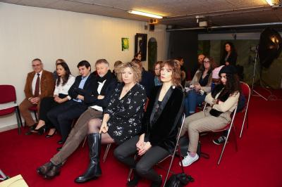 Un groupe de personnes pose devant une bannière, une femme au centre tient un diplôme.