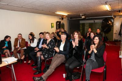 Un groupe de personnes pose devant une bannière, une femme au centre tient un diplôme.