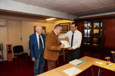 Un groupe de personnes pose devant une bannière, une femme au centre tient un diplôme.