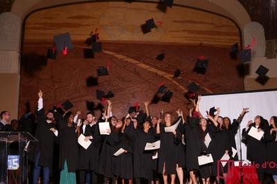 Un groupe de personnes pose devant une bannière, une femme au centre tient un diplôme.