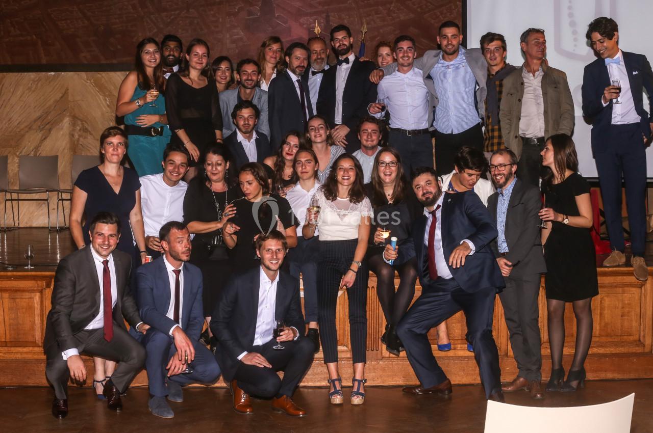 Un groupe de personnes posant ensemble dans une salle avec un décor en bois, certaines tenant des verres.