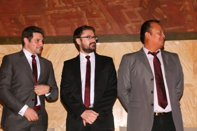 Un groupe de personnes pose devant une bannière, une femme au centre tient un diplôme.