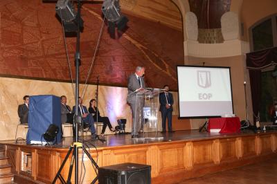 Un groupe de personnes pose devant une bannière, une femme au centre tient un diplôme.