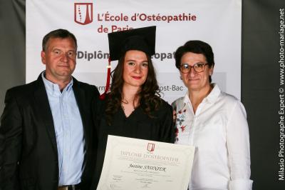 Un groupe de personnes pose devant une bannière, une femme au centre tient un diplôme.