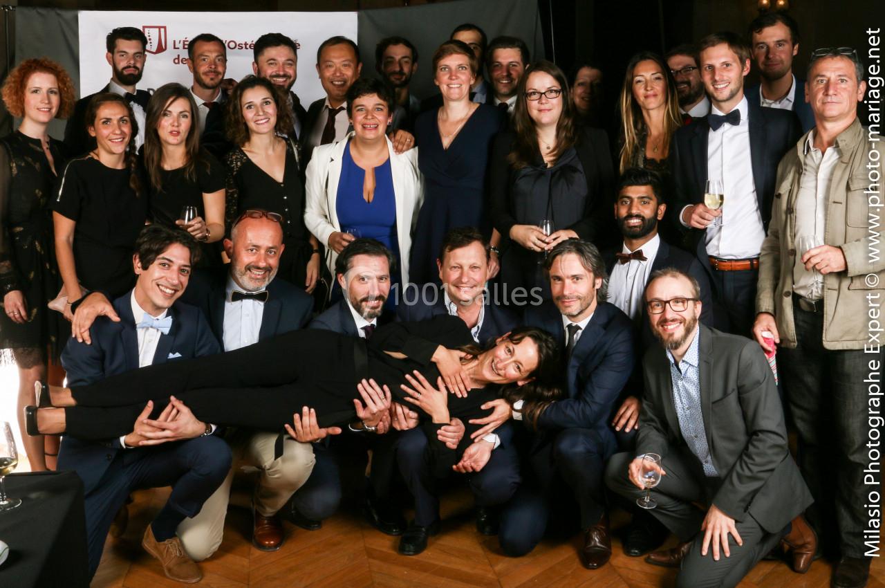 Un groupe de personnes posant ensemble lors d'un événement, certaines souriantes et habillées de manière élégante.