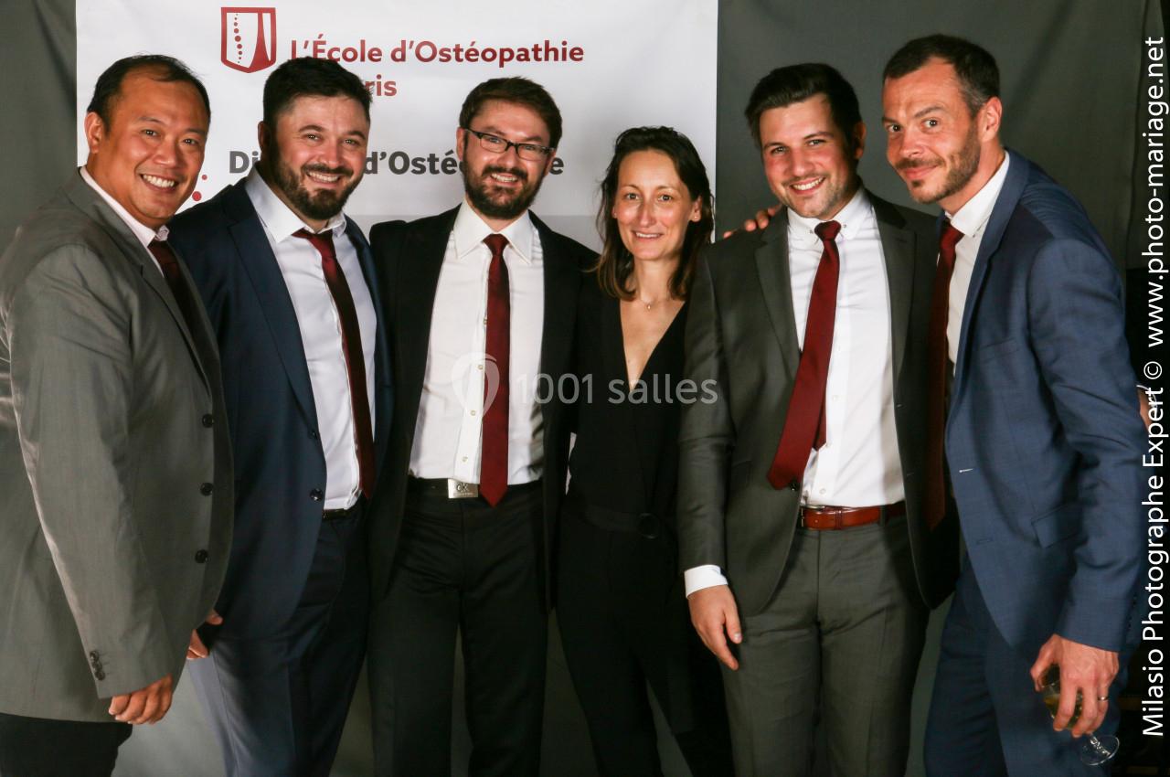 Un groupe de six personnes en tenue formelle posant devant une bannière d'une école d'ostéopathie.