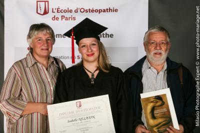 Un groupe de personnes pose devant une bannière, une femme au centre tient un diplôme.