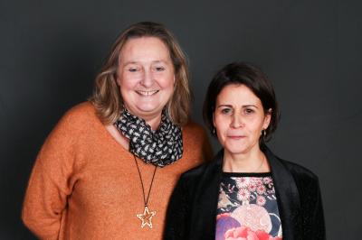 Un groupe de personnes pose devant une bannière, une femme au centre tient un diplôme.
