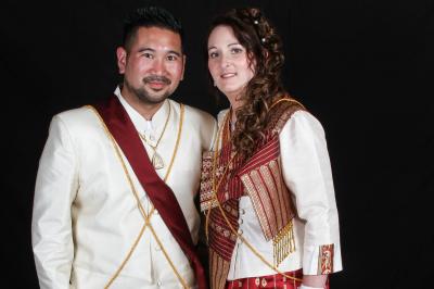 Un couple en tenue de mariage danse sur une place pavée devant un bâtiment historique.