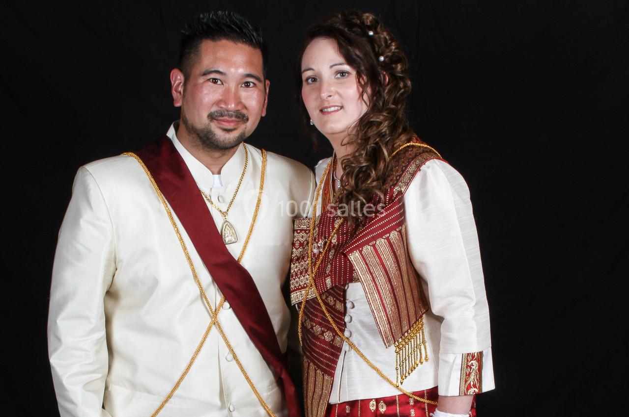 Un homme et une femme en tenues traditionnelles posent devant un fond noir.