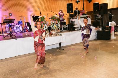 Un couple en tenue de mariage danse sur une place pavée devant un bâtiment historique.