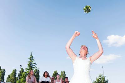Un couple en tenue de mariage danse sur une place pavée devant un bâtiment historique.
