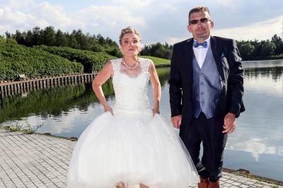 Un couple en tenue de mariage danse sur une place pavée devant un bâtiment historique.