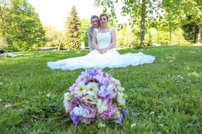 Un couple en tenue de mariage danse sur une place pavée devant un bâtiment historique.