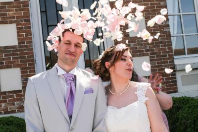 Un couple en tenue de mariage danse sur une place pavée devant un bâtiment historique.
