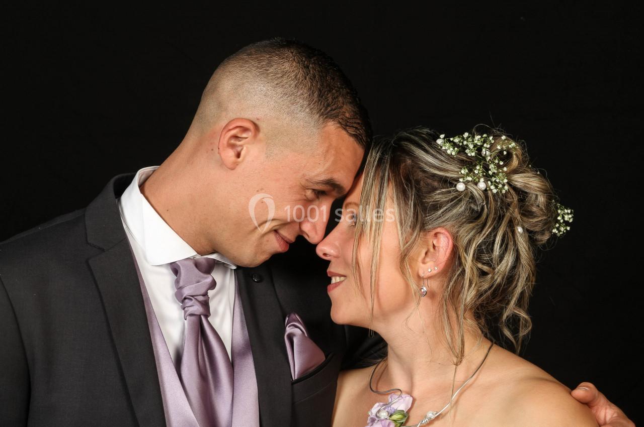 Un couple habillé élégamment se regarde avec tendresse, sur un fond noir.