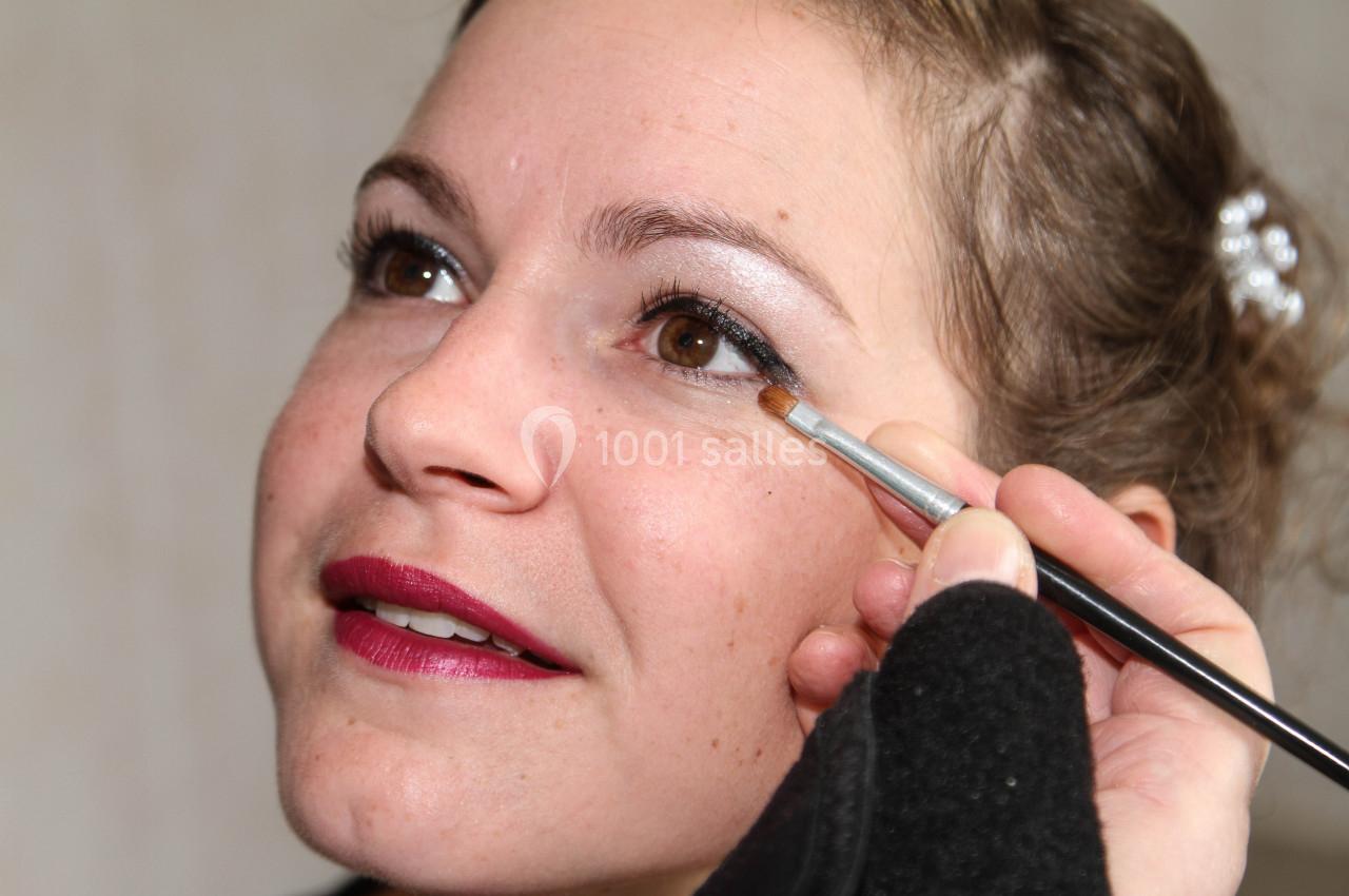 Femme se faisant appliquer de l'eyeliner noir sur la paupière supérieure avec un pinceau fin.
