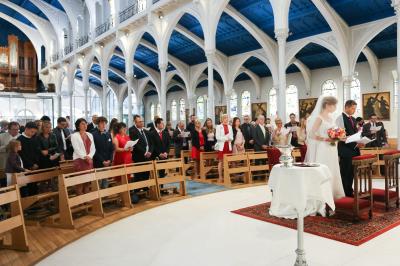 Un couple en tenue de mariage danse sur une place pavée devant un bâtiment historique.