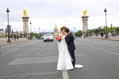 Un couple en tenue de mariage danse sur une place pavée devant un bâtiment historique.