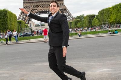 Un couple en tenue de mariage danse sur une place pavée devant un bâtiment historique.