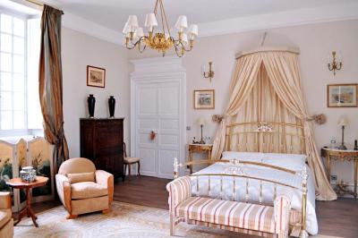 Miniature Location salle Bouesse (Indre) - Chateau de Bouesse en Berry #33 Vase de pivoines roses sur une table en bois, entouré de livres, chandeliers et fauteuils dans un salon élégant.