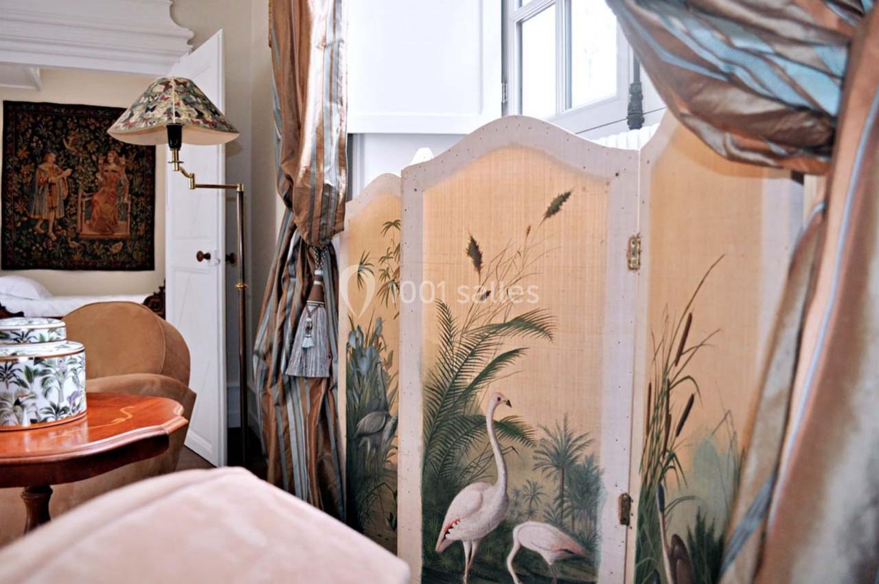 Paravent décoratif avec illustrations de flamants roses et végétation, placé dans un intérieur élégant et lumineux.