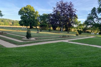 Miniature Location salle Bouesse (Indre) - Chateau de Bouesse en Berry #9 Vase de pivoines roses sur une table en bois, entouré de livres, chandeliers et fauteuils dans un salon élégant.