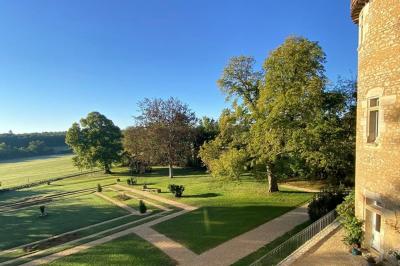 Miniature Location salle Bouesse (Indre) - Chateau de Bouesse en Berry #6 Vase de pivoines roses sur une table en bois, entouré de livres, chandeliers et fauteuils dans un salon élégant.