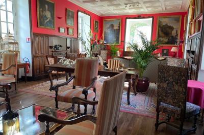 Miniature Location salle Bouesse (Indre) - Chateau de Bouesse en Berry #63 Vase de pivoines roses sur une table en bois, entouré de livres, chandeliers et fauteuils dans un salon élégant.