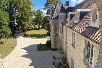 Miniature Location salle Bouesse (Indre) - Chateau de Bouesse en Berry #77 Vase de pivoines roses sur une table en bois, entouré de livres, chandeliers et fauteuils dans un salon élégant.