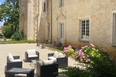 Miniature Location salle Bouesse (Indre) - Chateau de Bouesse en Berry #82 Vase de pivoines roses sur une table en bois, entouré de livres, chandeliers et fauteuils dans un salon élégant.