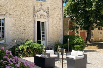 Miniature Location salle Bouesse (Indre) - Chateau de Bouesse en Berry #83 Vase de pivoines roses sur une table en bois, entouré de livres, chandeliers et fauteuils dans un salon élégant.