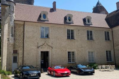 Miniature Location salle Bouesse (Indre) - Chateau de Bouesse en Berry #87 Vase de pivoines roses sur une table en bois, entouré de livres, chandeliers et fauteuils dans un salon élégant.