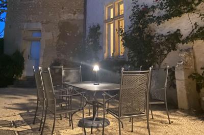 Miniature Location salle Bouesse (Indre) - Chateau de Bouesse en Berry #91 Vase de pivoines roses sur une table en bois, entouré de livres, chandeliers et fauteuils dans un salon élégant.