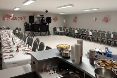 Parking extérieur de nuit avec une voiture stationnée, éclairé par des lampadaires et entouré de haies et d'arbres.