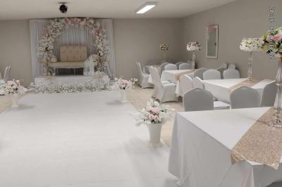 Parking extérieur de nuit avec une voiture stationnée, éclairé par des lampadaires et entouré de haies et d'arbres.