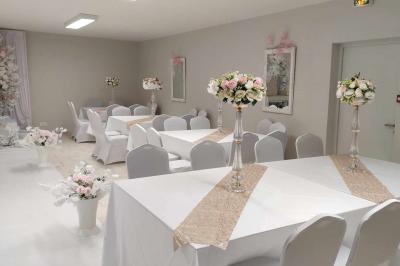 Parking extérieur de nuit avec une voiture stationnée, éclairé par des lampadaires et entouré de haies et d'arbres.