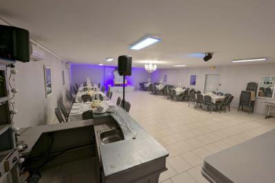 Parking extérieur de nuit avec une voiture stationnée, éclairé par des lampadaires et entouré de haies et d'arbres.