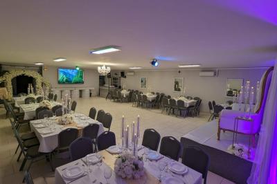 Parking extérieur de nuit avec une voiture stationnée, éclairé par des lampadaires et entouré de haies et d'arbres.