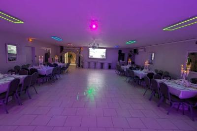 Parking extérieur de nuit avec une voiture stationnée, éclairé par des lampadaires et entouré de haies et d'arbres.