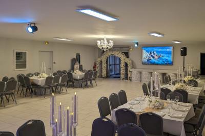 Parking extérieur de nuit avec une voiture stationnée, éclairé par des lampadaires et entouré de haies et d'arbres.