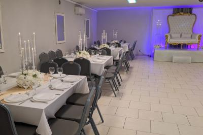 Parking extérieur de nuit avec une voiture stationnée, éclairé par des lampadaires et entouré de haies et d'arbres.