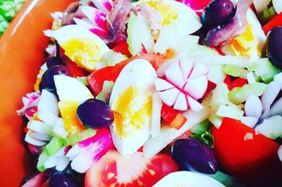 Assiette de légumes variés dressés avec soin, comprenant asperges, carottes, chou-fleur, roquette et sauce décorative.