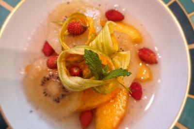 Assiette de légumes variés dressés avec soin, comprenant asperges, carottes, chou-fleur, roquette et sauce décorative.