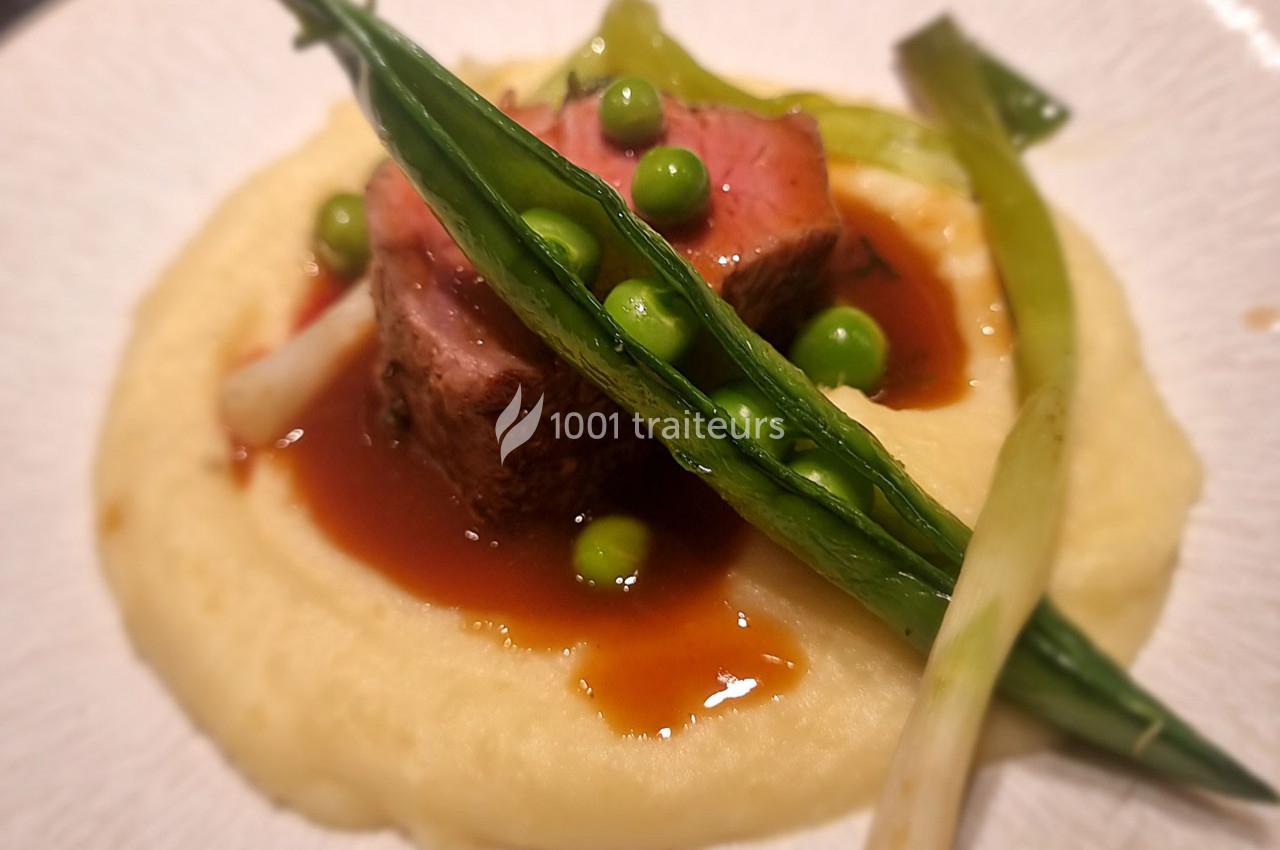 Plat composé de viande rosée, purée onctueuse, sauce brune, petits pois et oignons verts en garniture.