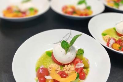Assiette de légumes variés dressés avec soin, comprenant asperges, carottes, chou-fleur, roquette et sauce décorative.